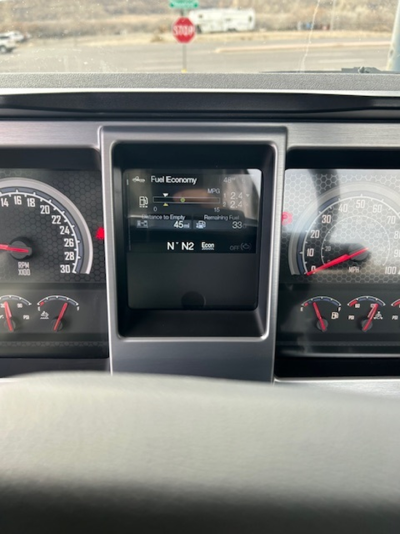 Dashboard panel of 2026 Mack GR64B showing fuel economy display and gauges with digital readout.