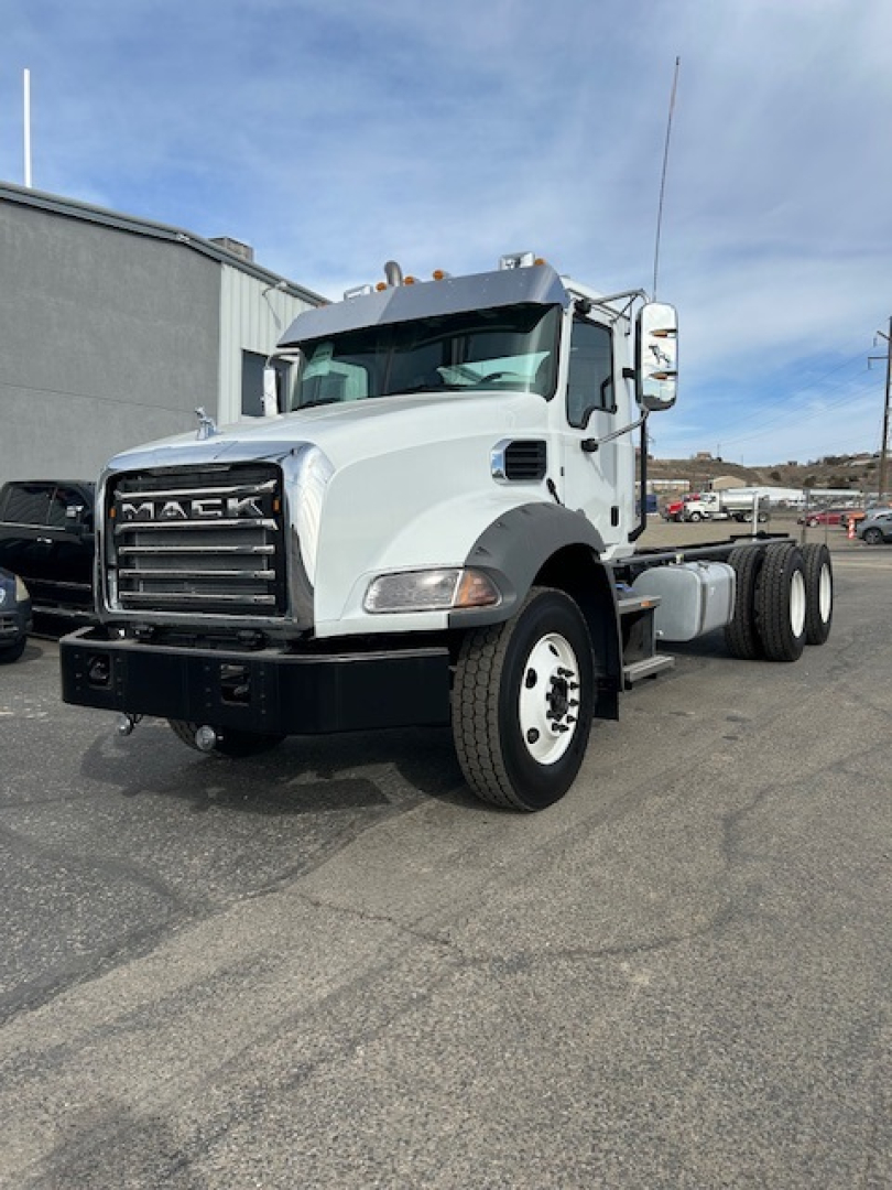 Mack GR64B vacuum tanker truck shown in side-front view with white cab and black grille, displaying Mack emblem on grille.