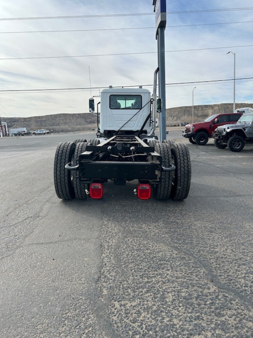 Rear view of a new Mack GR64B vacuum truck chassis showing dual rear axles, taillights, and hitch components.