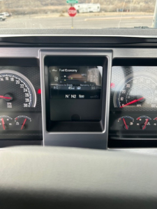 Dashboard panel of 2026 Mack GR64B showing fuel economy display and gauges with digital readout.
