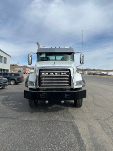 Front view of a white 2026 Mack GR64B heavy-duty truck with chrome grille, large bumper, and amber marker lights on the cab roof.