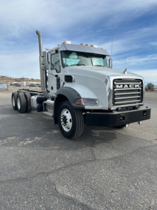Truck cab front-right view of a Mack GR64B vacuum tanker chassis, showing grille, Mack emblem, large side exhaust, and front bumper.
