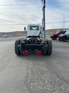Rear view of a new Mack GR64B vacuum truck chassis showing dual rear axles, taillights, and hitch components.