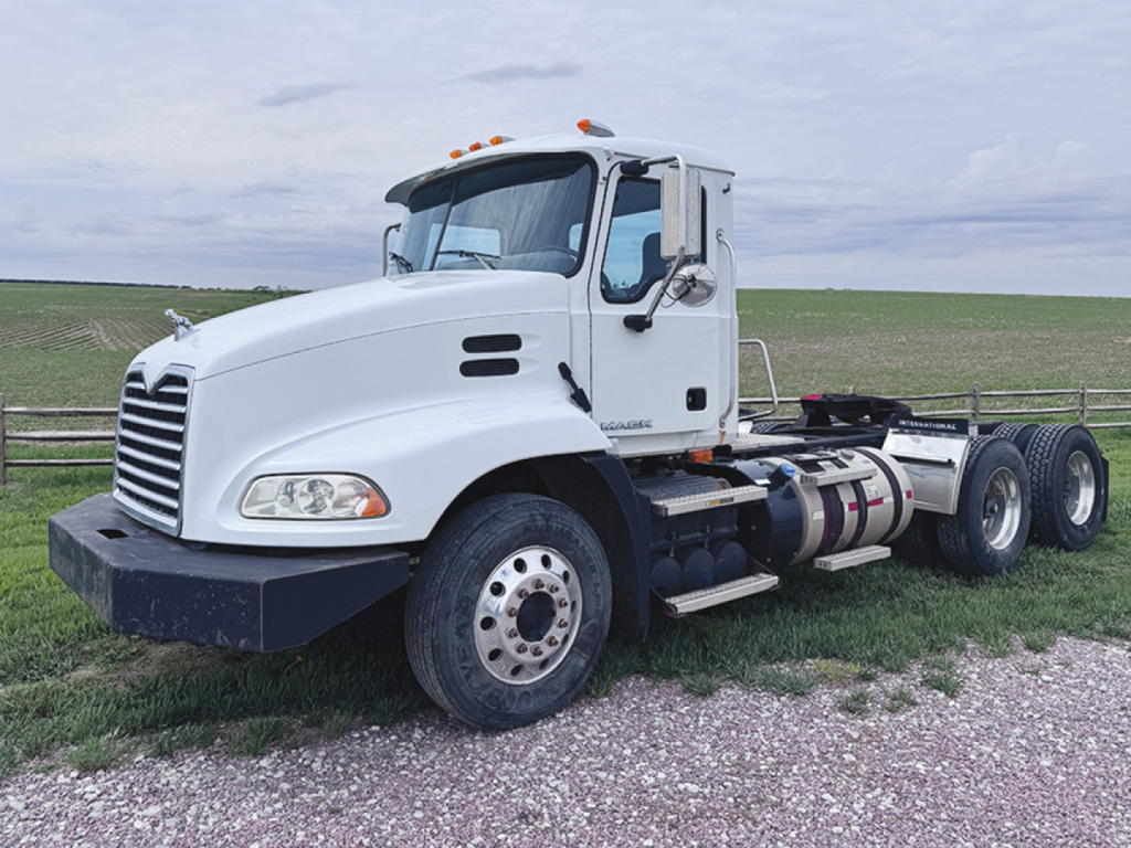 Truck deck space showing 2013 Mack CXU613 conventional daycab, white cab, dual rear axles, stock number 551212, side view.