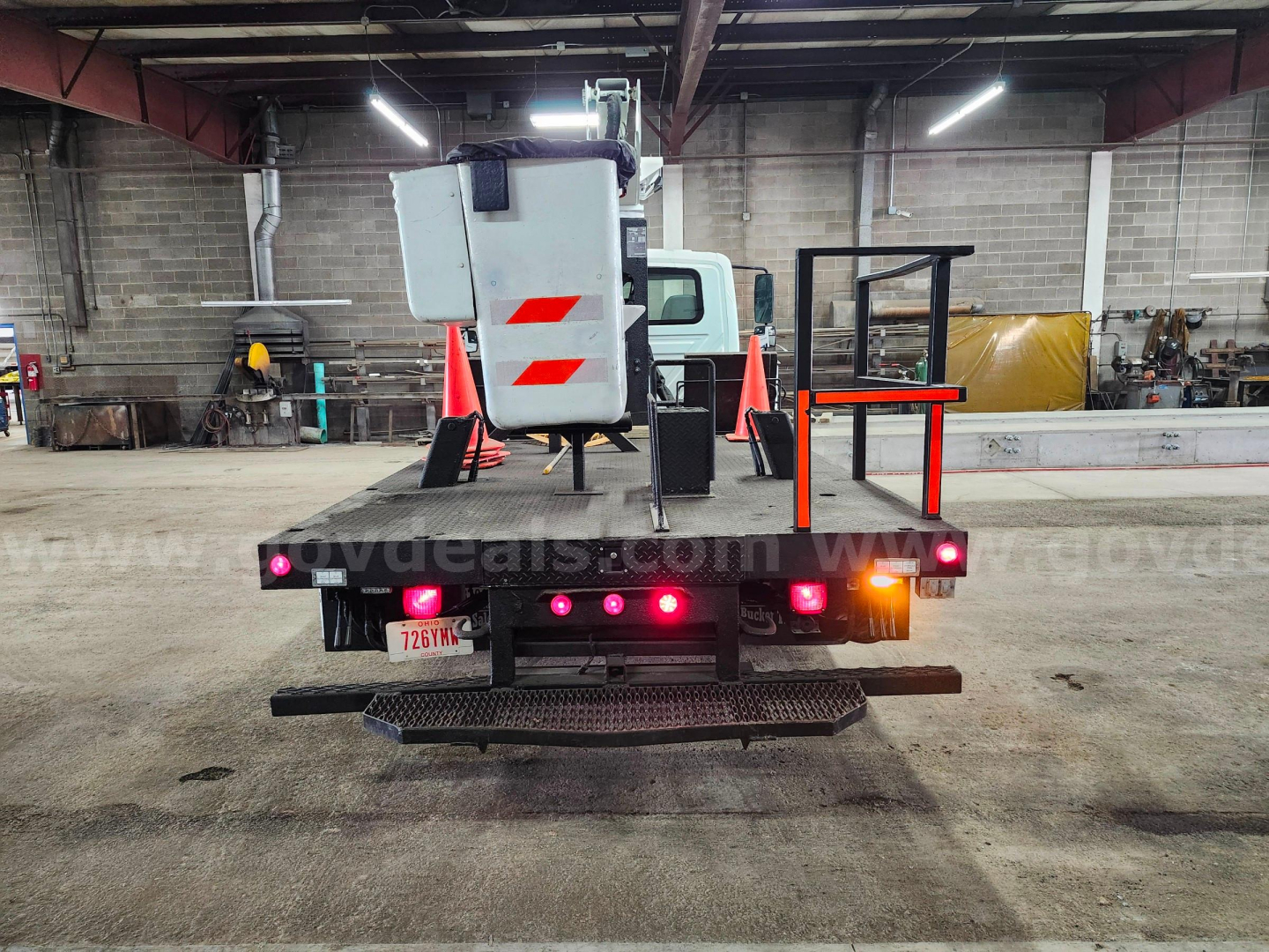 Back of a 2004 International 4200 bucket truck showing rear equipment, lights, and safety cones.
