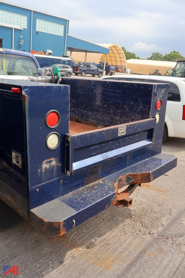 Rear view of a blue Ford F-350 utility truck bed with steel toolbox and step bumper