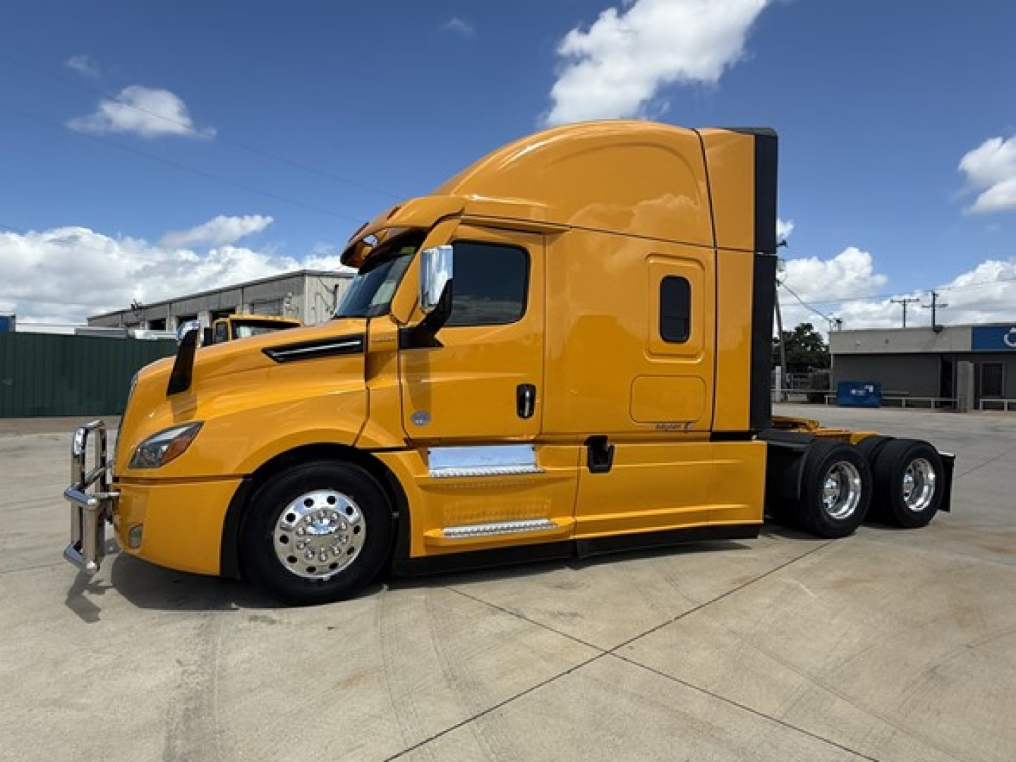 Freightliner Cascadia 126 sleeper cab tractor side view in yellow with chrome wheels and dual rear axles.
