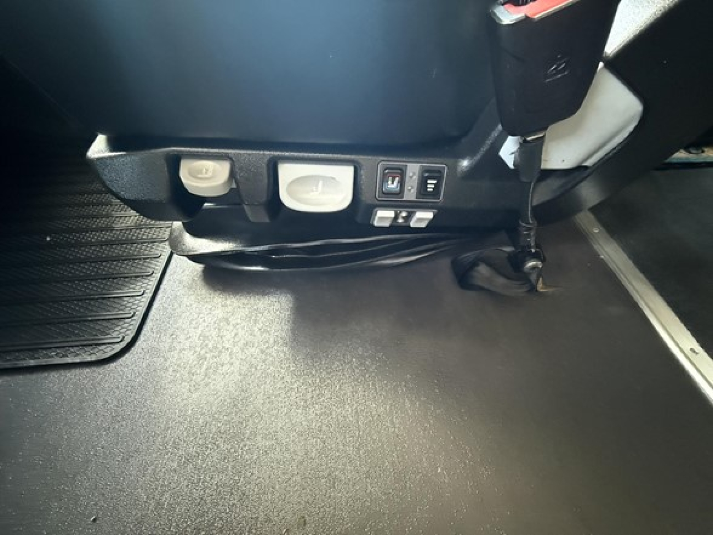 Cab interior floor area and lower dash of a Freightliner Cascadia showing switches and a seat base, no legible model text visible.