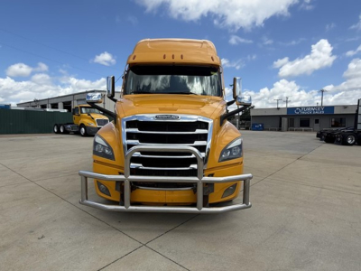 Freightliner Cascadia 126 front view showing chrome grille, bumper guard, and yellow cab in a dealership lot.