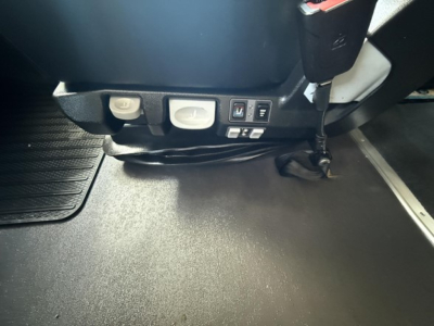 Cab interior floor area and lower dash of a Freightliner Cascadia showing switches and a seat base, no legible model text visible.