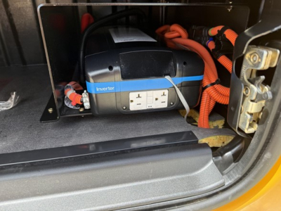 Inverter unit in Freightliner Cascadia 126 engine bay showing labeled inverter with control panel and orange battery cables.