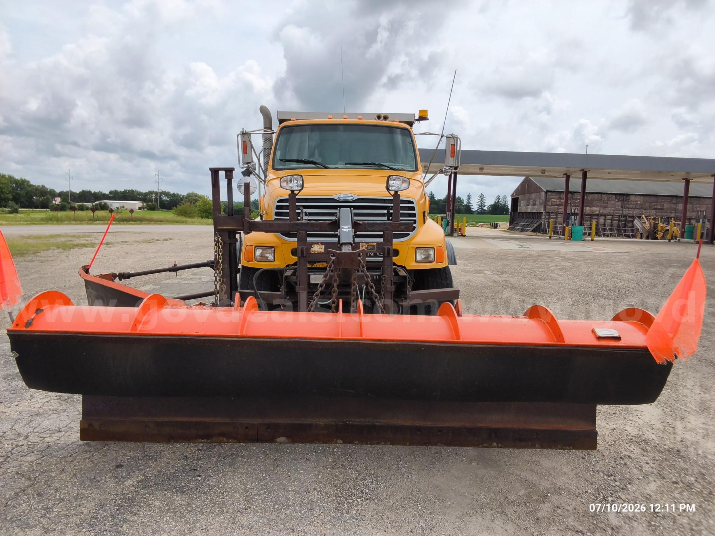 Front view of a yellow 2008 Sterling LT8500 dump truck with a large orange snow plow blade attachment in front.