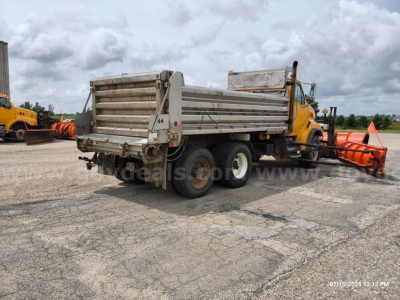 Dump truck with yellow cab and silver dump bed, side view showing rear wheels and tailgate.