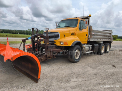 Orange Sterling LT8500 dump truck with snowplow blade attachment in front, side view showing long dump bed and dual rear axles.