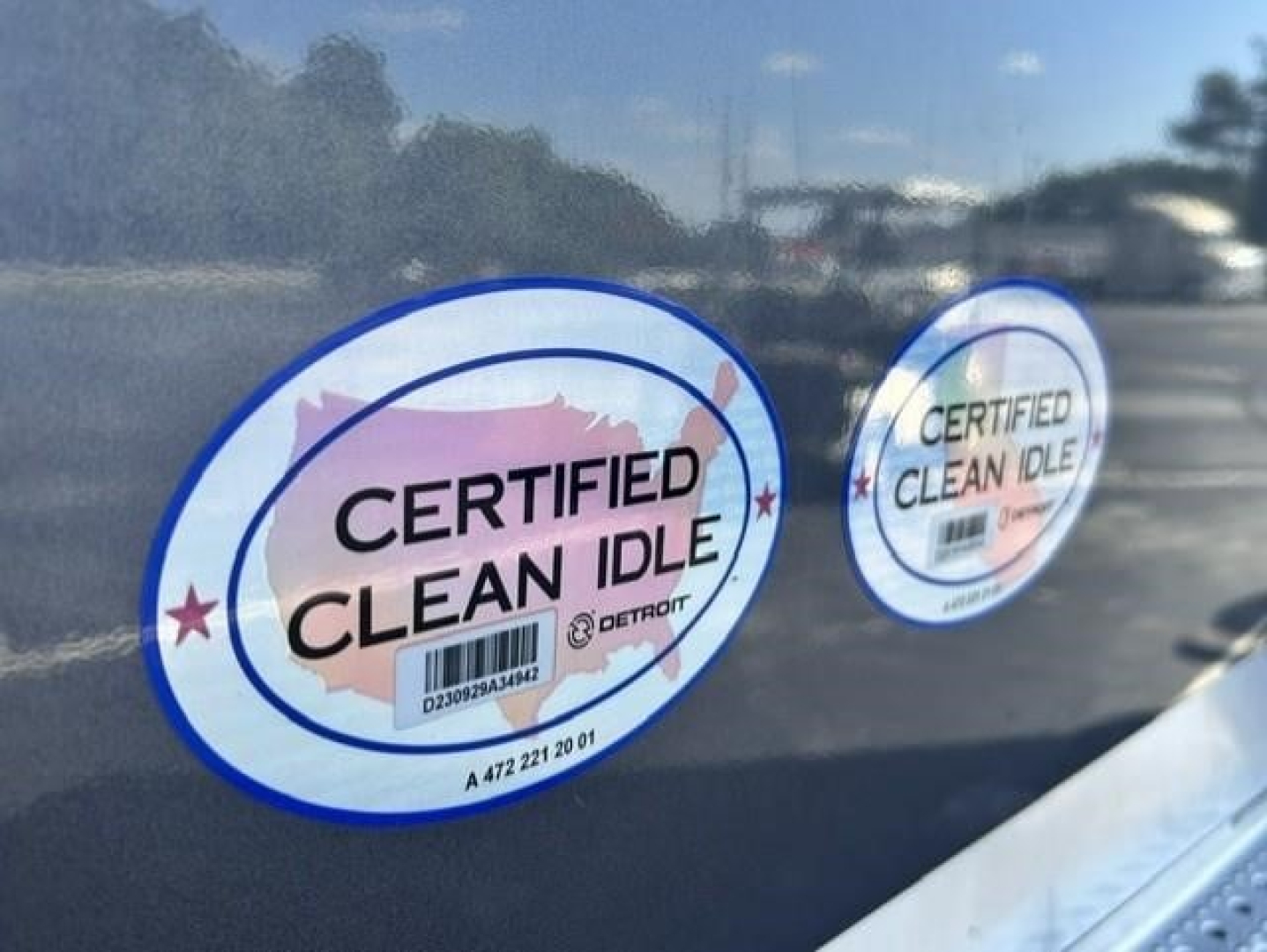 Sticker labels reading Certified Clean Idle on Freightliner Cascadia 126 window with blue circle border stickers.