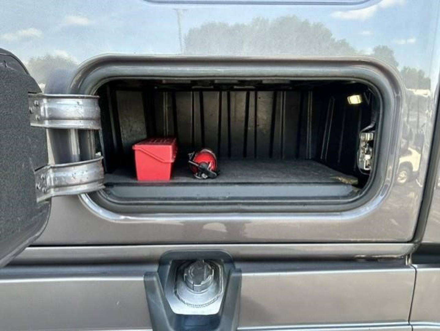 Freightliner Cascadia 126 fuel or storage hatch open showing interior with red storage box and safety helmet at front of storage compartment.