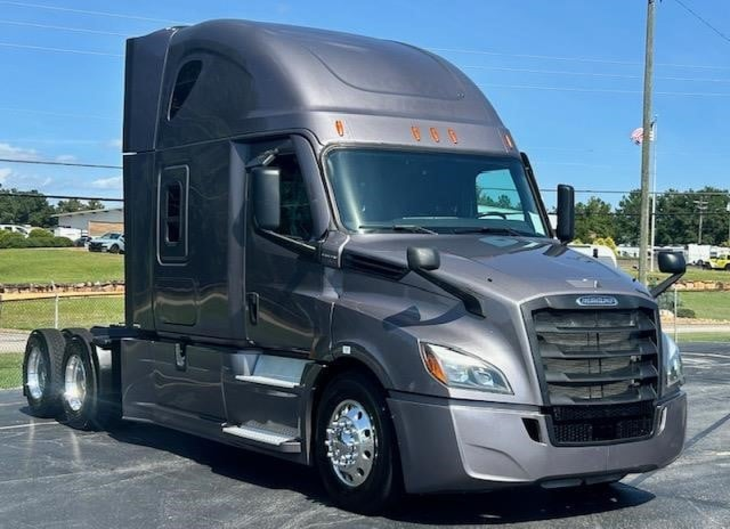 Truck cab exterior of a 2023 Freightliner Cascadia 126 with gray metallic paint, front grille, large windshield, and dual rear axles