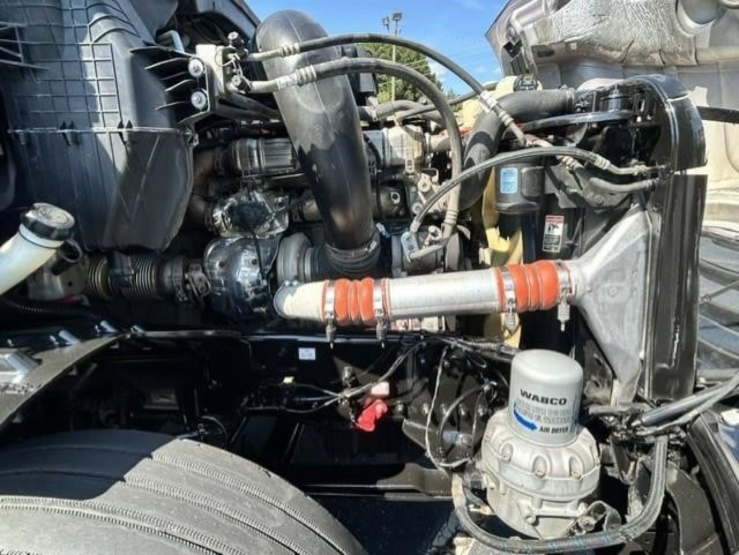 Freightliner Cascadia engine bay showing coolant hoses, air filter, and fluid reservoirs with Warco filtration canister visible.