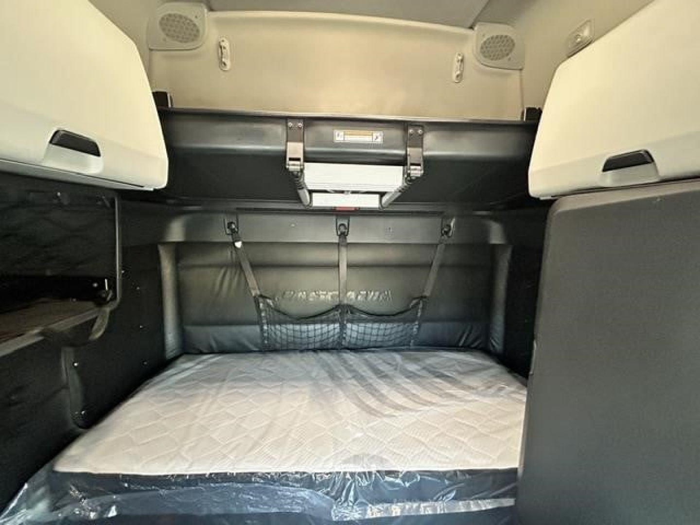 Truck sleeper cabin interior with a bed area and storage pockets; no legible labels visible in image.