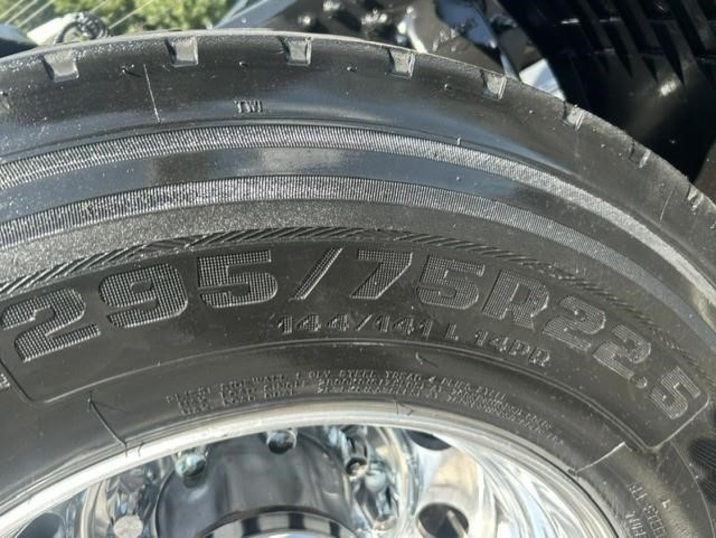 Truck tire with tread and sidewall markings, showing tire size 22.5 16? 235? Not clear. Visible characters include '??'