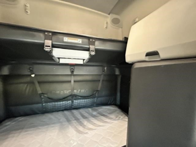 Freightliner Cascadia 126 sleeper cab interior bunk area showing storage nets and overhead panel with warning label.