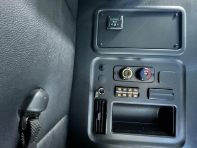 Dashboard area of a Freightliner Cascadia showing climate controls, 12V/aux outlets, and a storage pocket in a truck cabin.