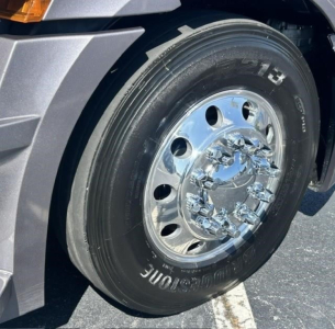 Front wheel and chrome hub of a Freightliner Cascadia 126 conventional sleeper truck showing Bridgestone tire and polished hub.