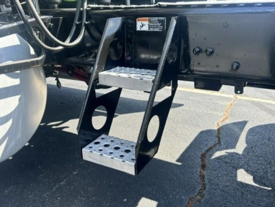 Freightliner Cascadia underside showing metal retractable steps with perforated platform and step supports.