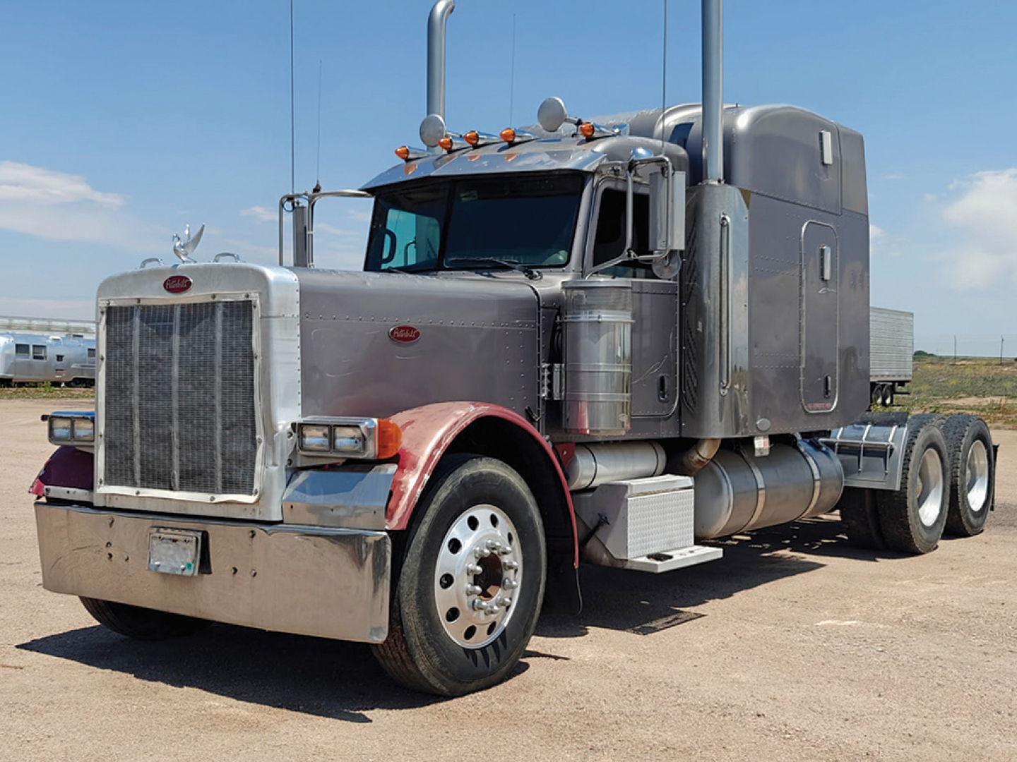 Peterbilt 379 UltraCab Extended Hood truck viewed from front-left, gray cab with chrome grille and dual exhaust stacks; large fuel tanks and steps visible; daytime outdoor lot.