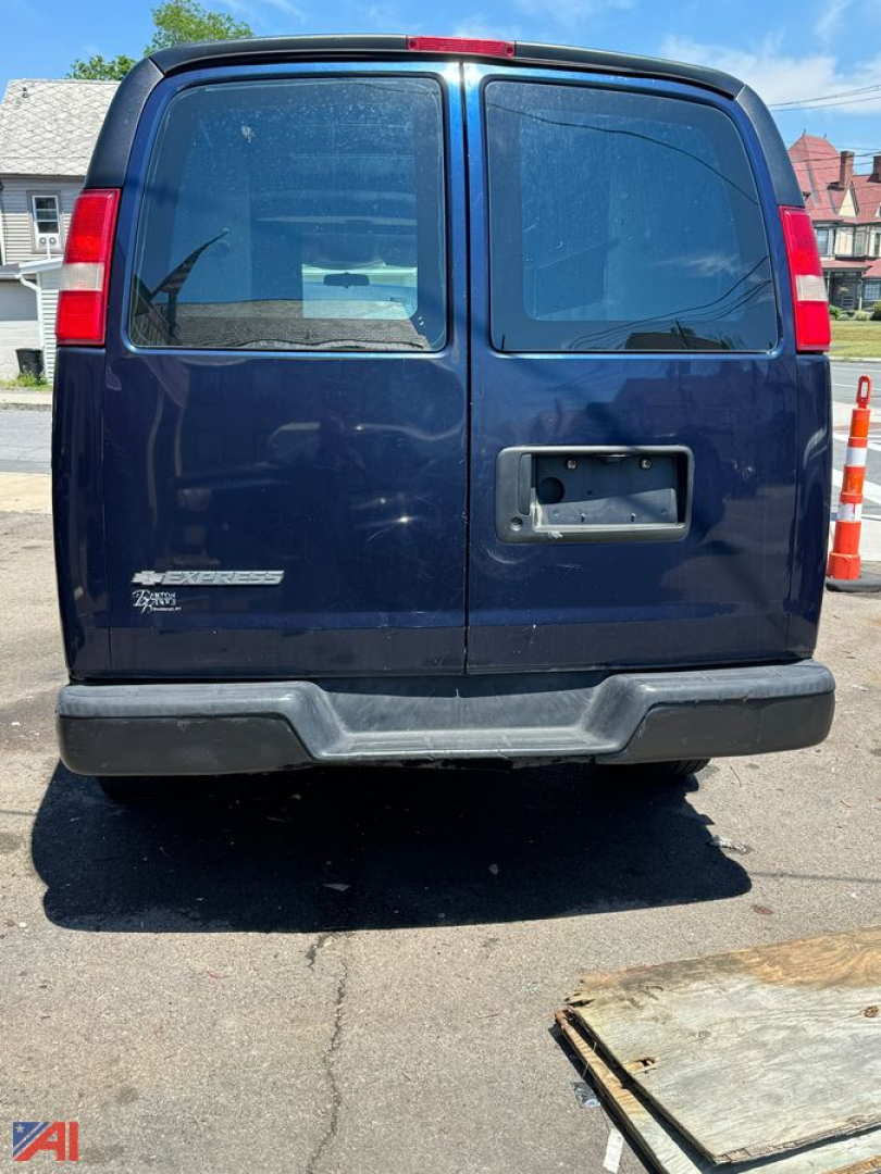 Rear view of a blue 2008 Chevrolet Express full-size cargo van, double rear doors, blank license plate area, bumper, and badge on left door.