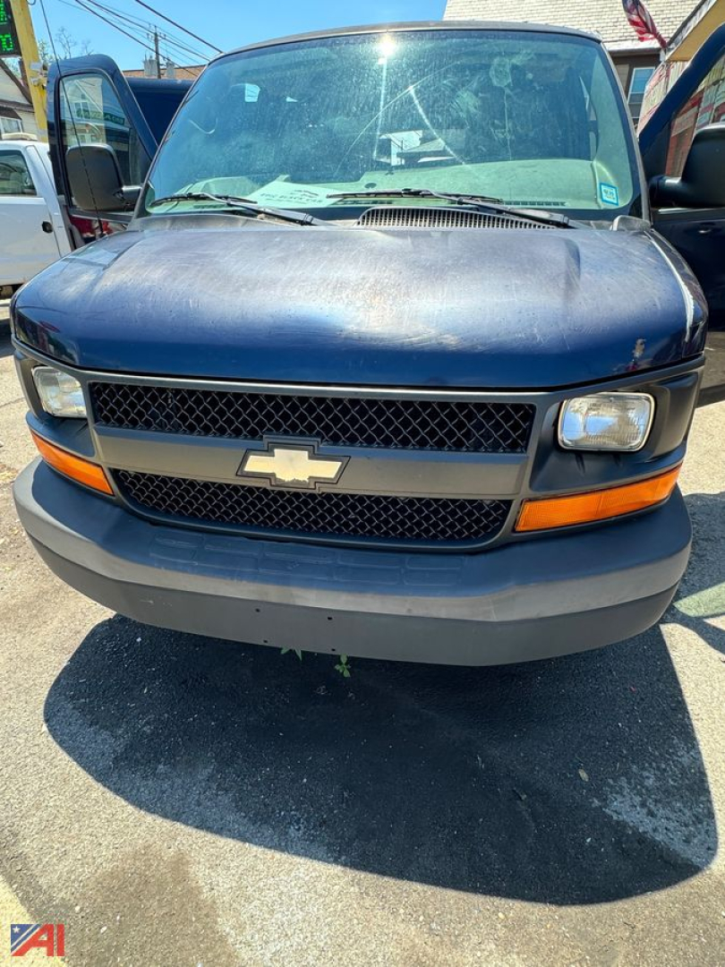 Chevrolet Express cargo van front view with Chevrolet emblem on grille, black mesh grille, amber turn signals, blue body, gray bumper.