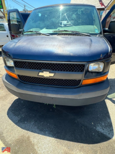 Chevrolet Express cargo van front view with Chevrolet emblem on grille, black mesh grille, amber turn signals, blue body, gray bumper.