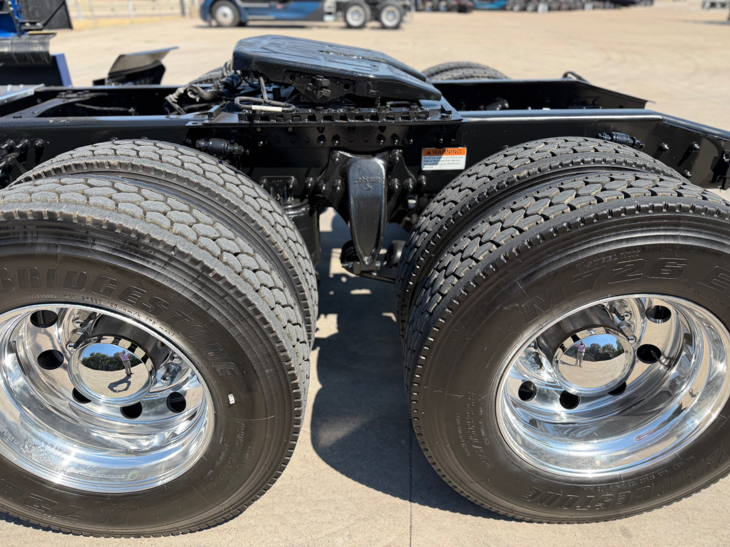 Dual rear axles with polished chrome wheels on a Freightliner tractor shows heavy-duty tires and suspension components.