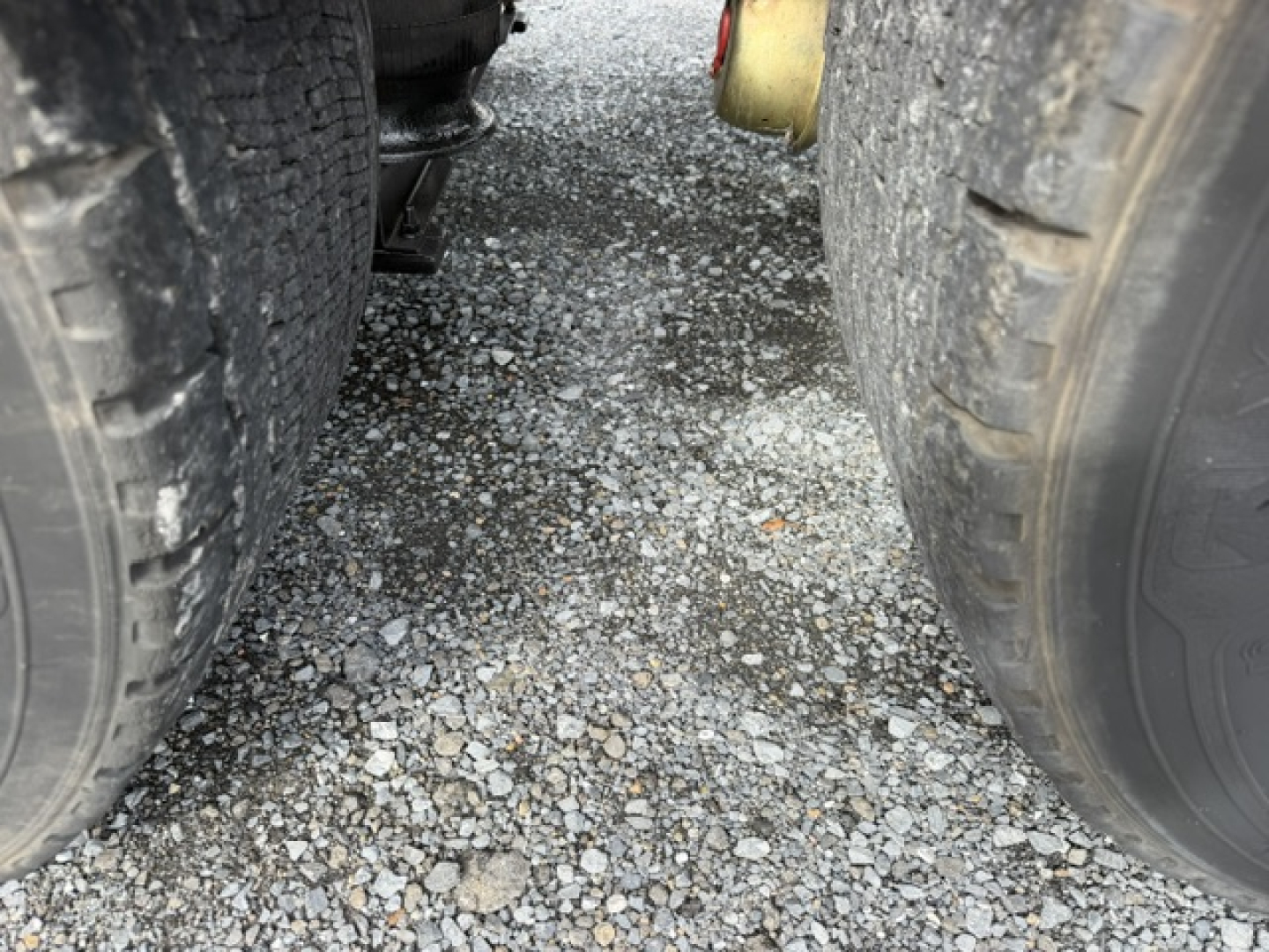 Volvo VNL64T300 truck undercarriage showing dual rear axles and ground between tires.