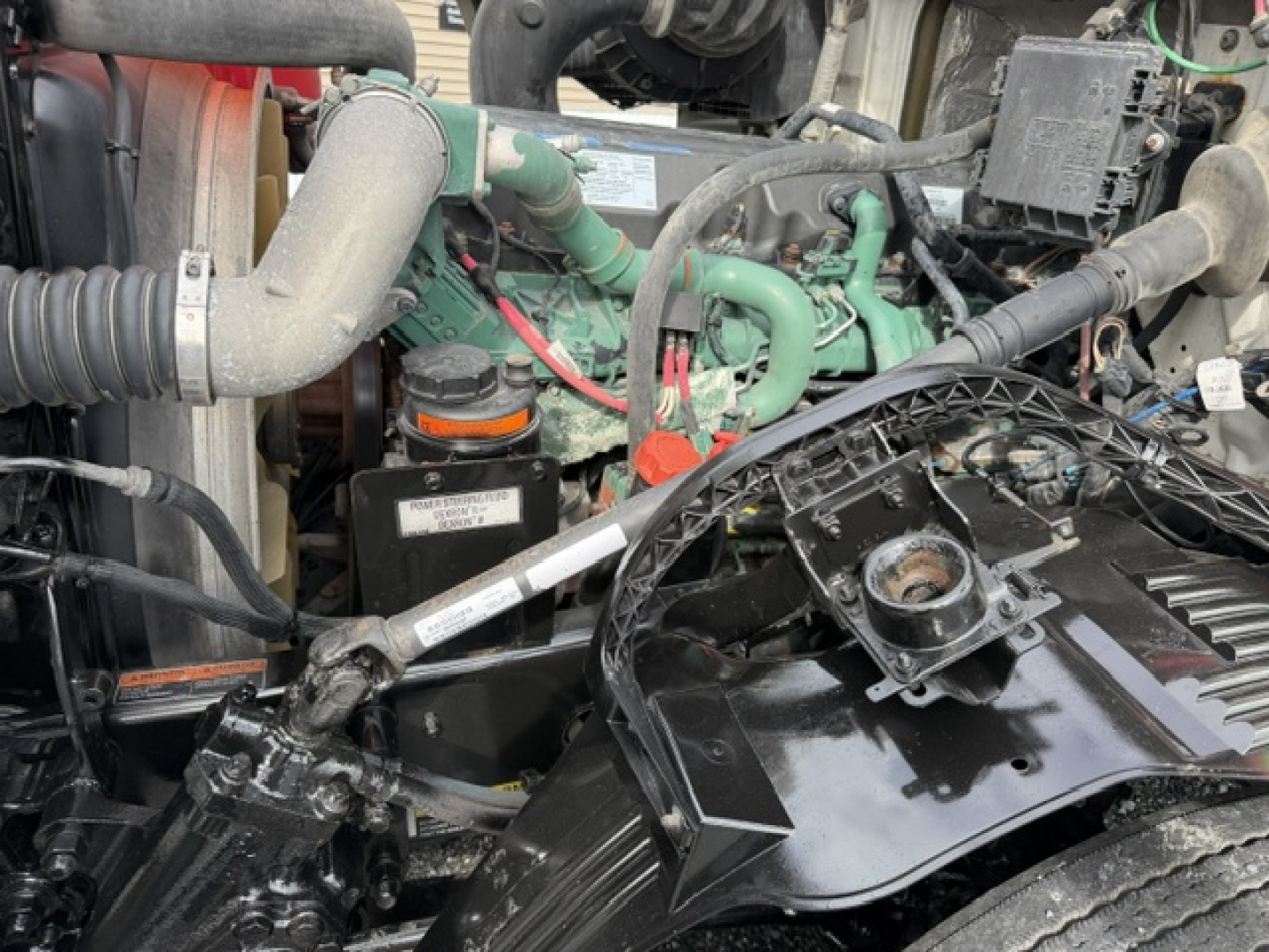 Volvo VNL64T300 engine bay showing green engine, hoses, and components with black coaxial wiring and metal brackets.