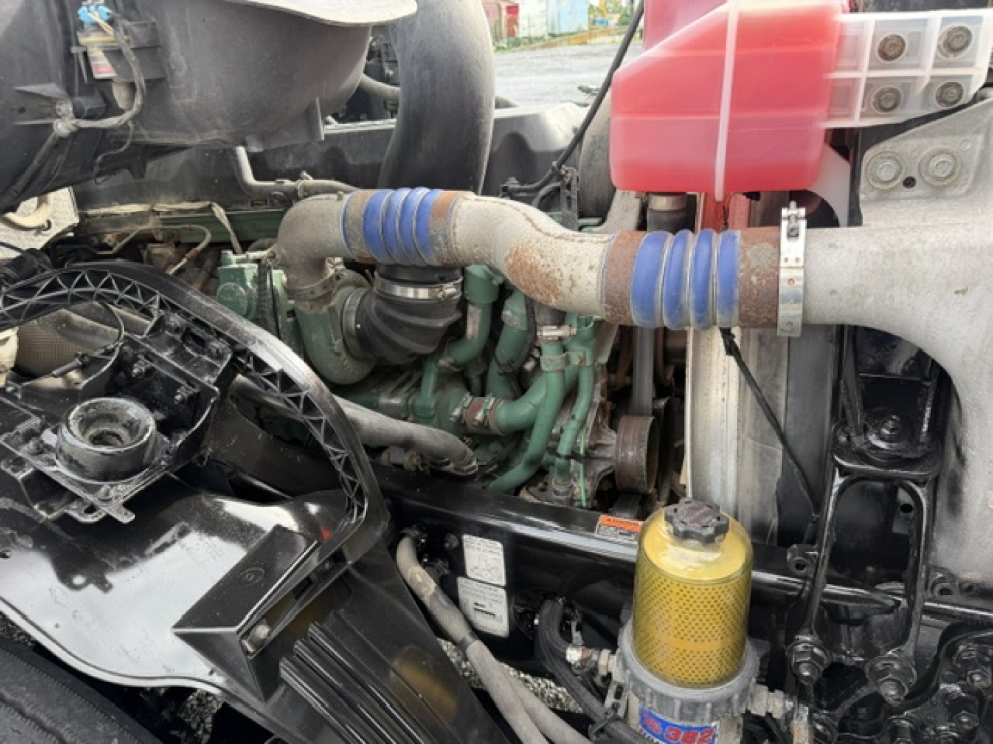 Volvo VNL64T300 engine bay with visible hoses, coolant reservoir, and filter canister.