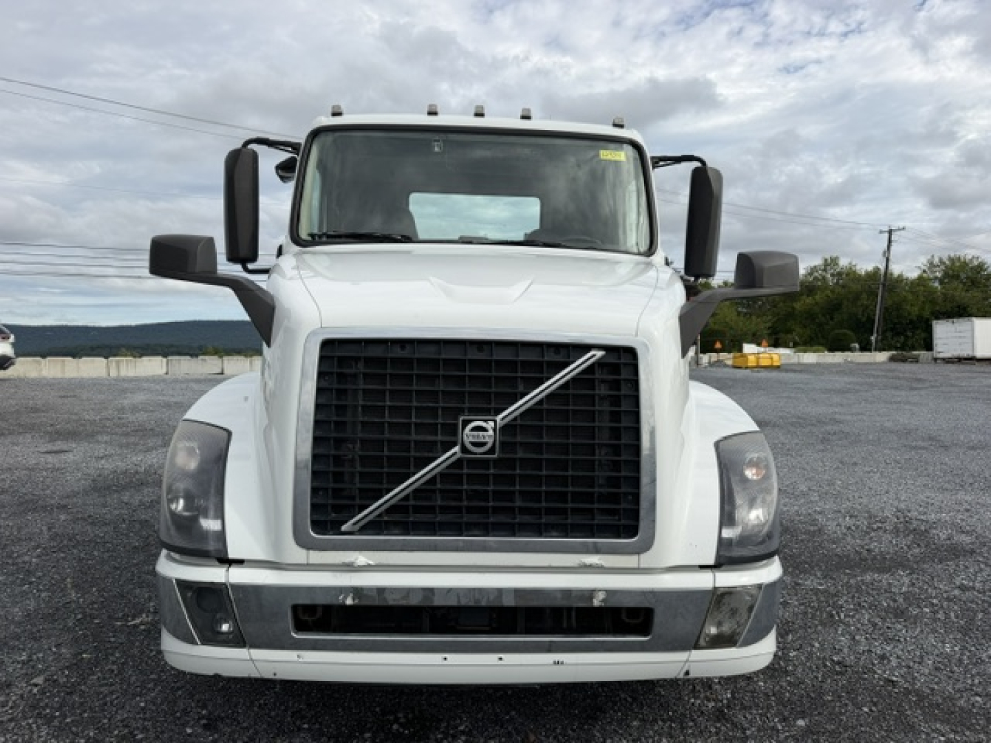 Volvo VNL64T300 front view showing large black grille with diagonal chrome bar and Volvo emblem, rectangular headlights, white cab, side mirrors.