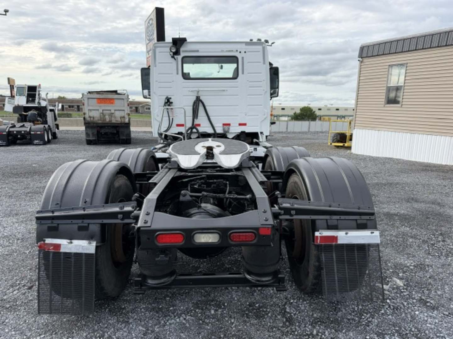 Rear view of a 2016 Volvo VNL64T300 conventional daycab truck chassis showing dual rear axles, fifth wheel, and mud flaps.