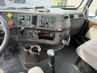 Volvo VNL64T300 cab interior showing dashboard controls, gear shifter, cup holders, and center console.