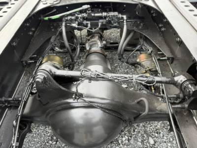 Drivetrain view under a Volvo VNL64T300 showing rear differential housing and drive shafts in a clean engine bay with hoses and components.