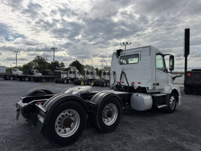 2016 Volvo VNL64T300 tractor viewed from rear-side showing fifth wheel and dual rear axles in a truck lot.