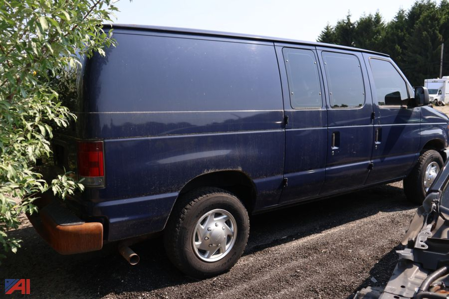 Ford E-250 cargo van with dark blue paint, side panels, rear quarter, and rear wheel; left rear taillight visible; exhaust tip under bumper.