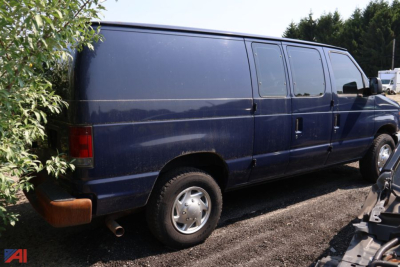 Ford E-250 cargo van with dark blue paint, side panels, rear quarter, and rear wheel; left rear taillight visible; exhaust tip under bumper.