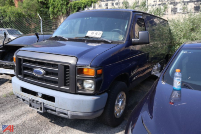 Ford E-Series van in blue, front-left view, cargo van, with black grille and gray bumper; stickered windshield and side mirror visible.