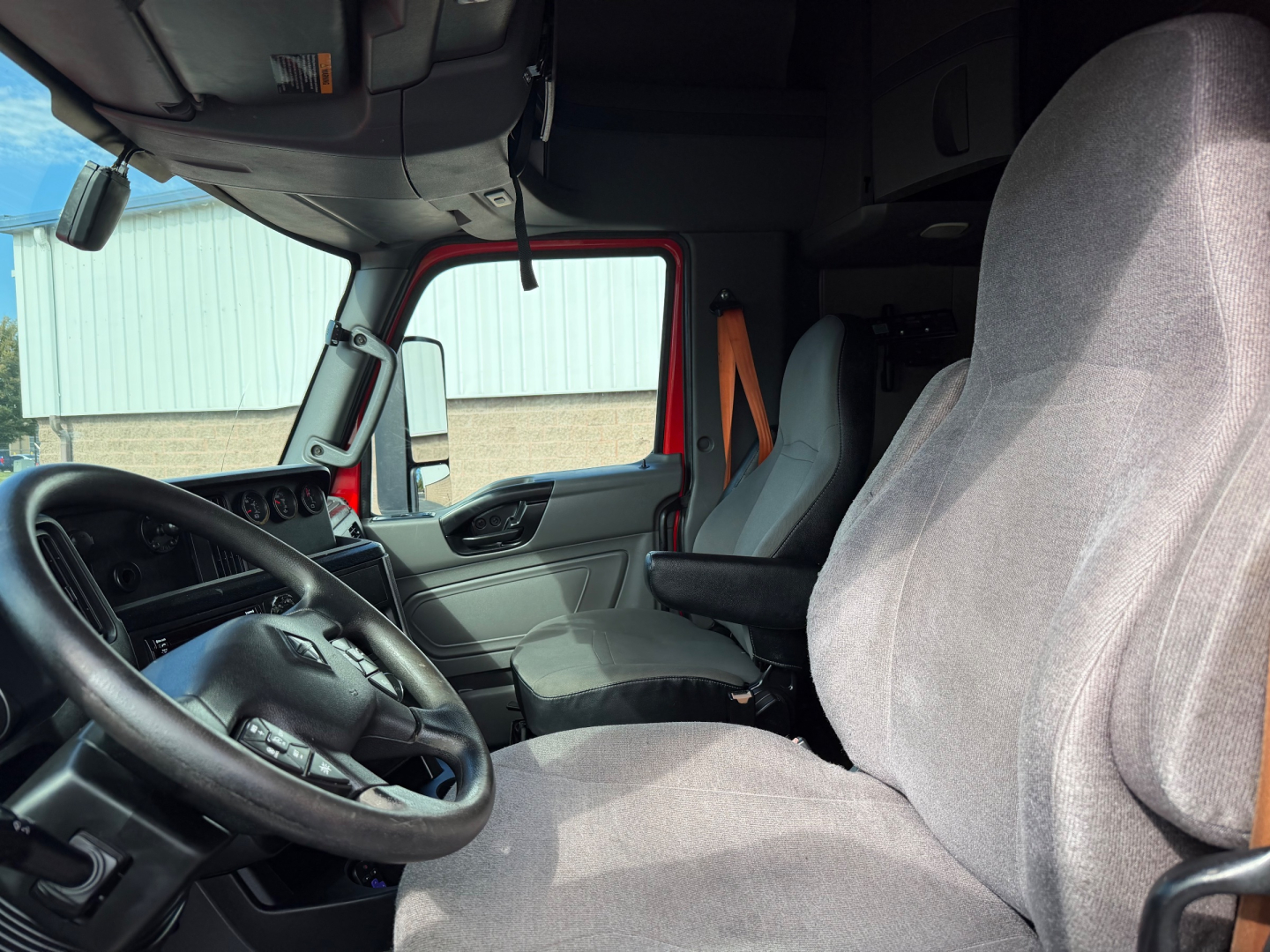 Interior of a 2020 International LT625 truck cab with steering wheel, driver seat, and passenger seat visible.