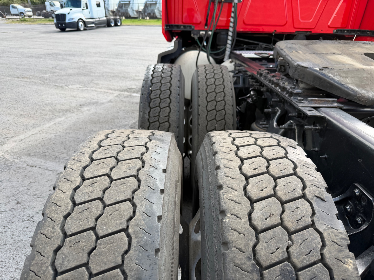 Truck rear dual tires on International LT625 tractor, view of the dual-wheel configuration and rear chassis with mudguard and red cab in background.