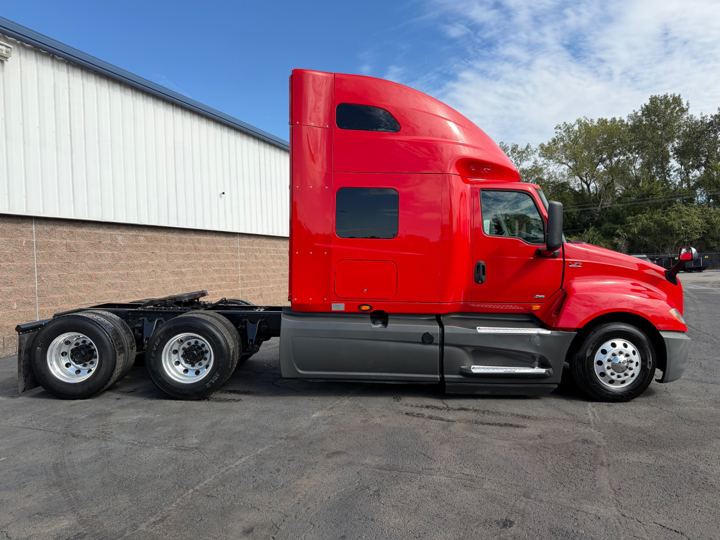 Red International LT625 tractor cab in side profile with sleeper, black chassis, and dual rear axles.