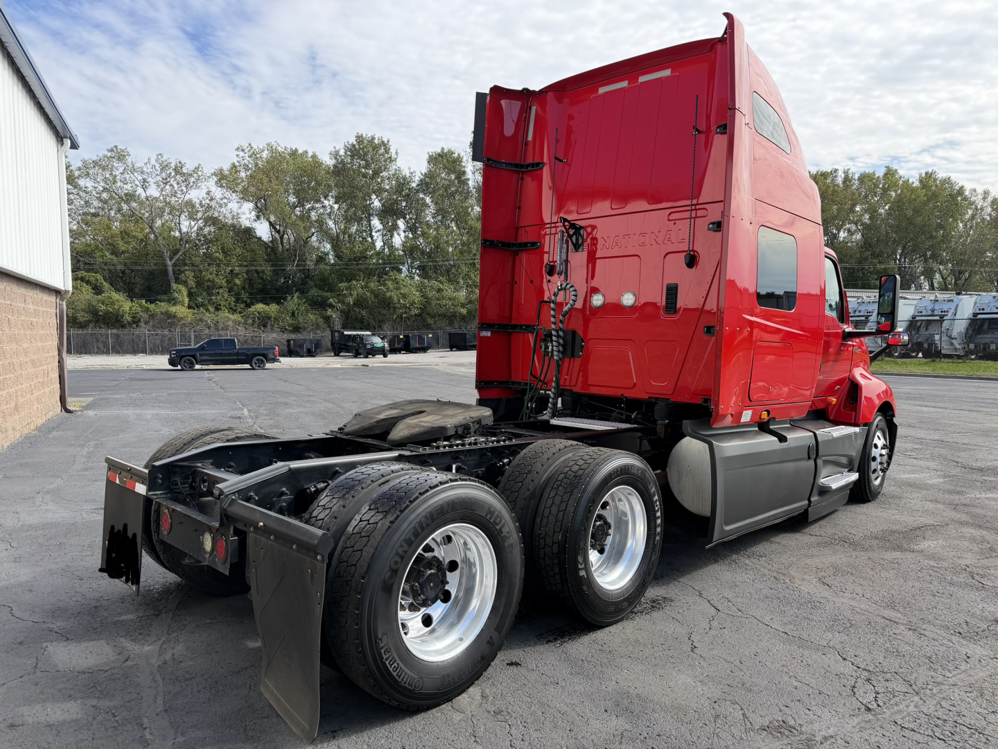 International LT625 truck tractor side/rear view showing red cab and dual rear axles with fifth-wheel and chassis, no visible damage.