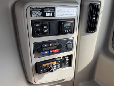 Dashboard controls and switches in a truck cab showing various labeled buttons and a digital display panel.