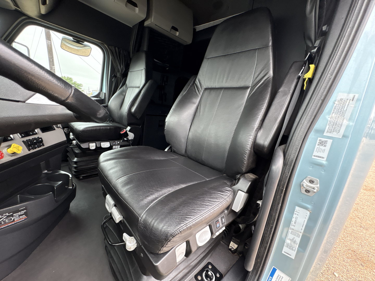Freightliner Cascadia 126 truck cab seat and dashboard area with control switches visible